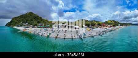Reihen von bunten banca Fischerbooten entlang der Küste am Mabua Beach, Surigao, einem beliebten Touristenstrand. Panoramablick. Stockfoto