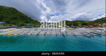Reihen von bunten banca Fischerbooten entlang der Küste am Mabua Beach, Surigao, einem beliebten Touristenstrand. Panoramablick. Stockfoto