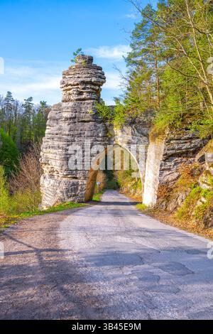 Das Pekar-Tor steht majestätisch im Böhmischen Paradies, Tschechien. Dieser atemberaubende Sandsteinbogen empfängt Besucher entlang einer ruhigen Straße, umgeben von üppigem Grün und natürlicher Schönheit. Stockfoto