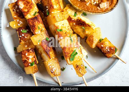 Gegrillter Tofu- und Ananassatay-Spieß mit würziger Erdnusssauce aus nächster Nähe. Gebratene halloumi-Käsekebabs. Veganes vegetarisches Essen. Stockfoto