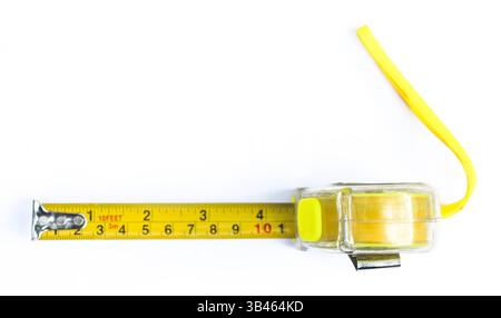 Erfasst ist ein verlängertes gelbes Metallmessband mit klaren Zentimetermarkierungen. Das Werkzeug liegt auf einer sauberen, hellweißen Oberfläche auf. Stockfoto
