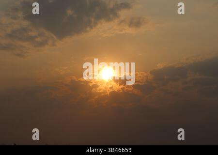 Goldenes Licht strömt durch die Wolken, wenn die Sonne untergeht, und schafft eine ruhige Sonnenuntergangsszene. Silhouette der Klingen sichtbar. Stockfoto