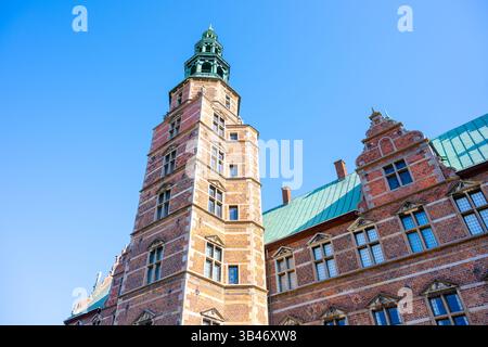 Der Rosenborg Schlossturm steht hoch in Kopenhagen und zeigt seine komplexe Architektur vor einem hellblauen Himmel. Besucher bewundern das einzigartige Design und die historische Bedeutung. Stockfoto