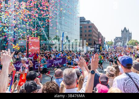 Lustige Läufer, die 2025 beim TCS London Marathon antreten, durchqueren Tower Hill, London, Großbritannien, nach Tower Bridge mit Unterstützern Stockfoto