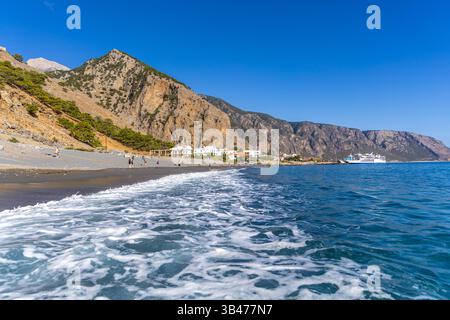 Kreta, Griechenland - 18. Oktober 2024: Wellen erreichen das Kieselufer von Agia Roumeli, wo die Samaria-Schlucht auf Kreta endet, umgeben von zerklüfteten Bergen und c Stockfoto