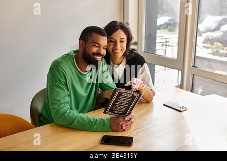 Ein Paar genießt die Gesellschaft des anderen, während er Kaffee trinkt, lacht und einen warmen Moment teilt. Stockfoto