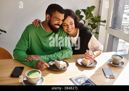 Ein Paar genießt süße Desserts, während es lacht und Wärme in einem charmanten Café teilt. Stockfoto