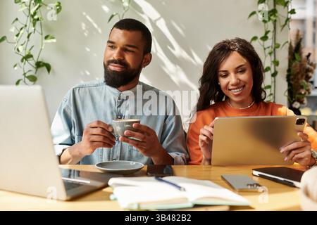 Ein afroamerikanisches Paar arbeitet gern fernab, während es bequem in einem Café sitzt. Stockfoto