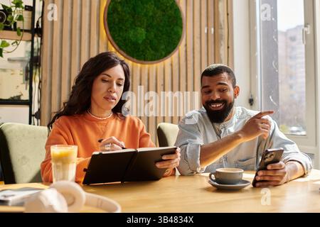 Ein afroamerikanisches Paar genießt Drinks und Gespräche in einem Café. Stockfoto