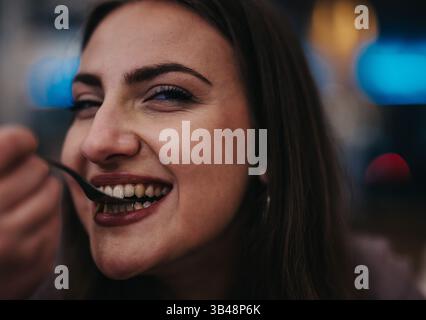 Lächelnde Frau, die abends in einer gemütlichen Loungebar Essen genießt Stockfoto