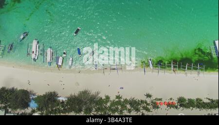Atemberaubender Blick aus der Vogelperspektive auf den White Beach in Boracay, Philippinen, mit zahlreichen bangka-Booten, die am Ufer ruhen, ergänzt durch das türkisfarbene Wasser und die üppige tropische Vegetation Stockfoto