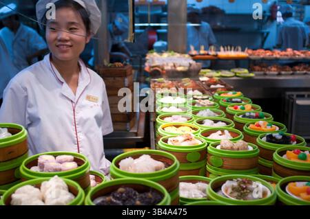 Restaurant in der Altstadt, Shanghai. Bamboo Dampfgarer Tabletts mit Dim Sum Auswahl in einem kleinen Restaurant im ehemaligen City God Temple an der Shanghai Old Street. Straße Seite chinesischen Dumpling oder Dim Sum Stall in der Altstadt, Shanghai, China. Xiaolongbao ist eine Art Dampfbrötchen (Baozi) aus der chinesischen Region Jiangnan, die besonders mit Shanghai und Wuxi assoziiert wird. Es wird traditionell in xiaolong zubereitet, kleine Bambus-Dampfkörbe, die ihnen ihren Namen geben. Xiaolongbao wird oft als eine Art "Klopfen" bezeichnet, sollte aber weder mit britischen oder amerikanischen Klößen noch mit chinesischen j verwechselt werden Stockfoto