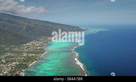 Die Luftdrohne fängt die atemberaubende Küste der Insel Tahiti ein und zeigt das pulsierende türkisfarbene Korallenriff, die üppigen grünen Berge, das Städtchen und den weiten pazifik Stockfoto