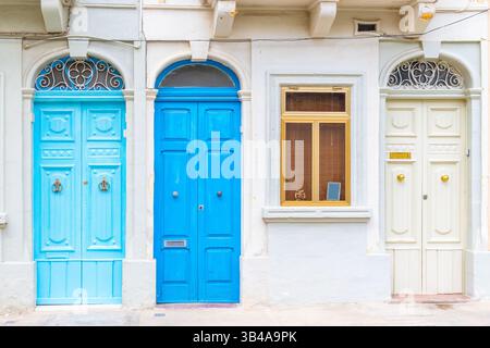 Fassade eines Wohngebäudes mit drei verschlossenen Holztüren in hellblau, blau und weiß gestrichen Stockfoto