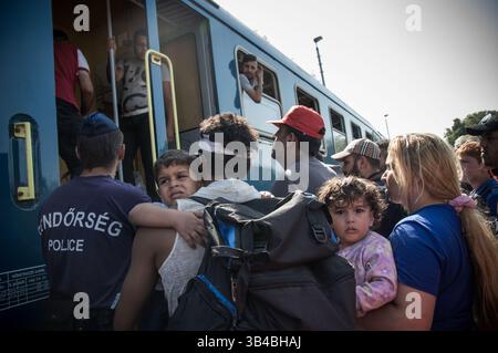 14. September 2015: Flüchtlinge sahen, wie sie in den Zug stürzten, der sie in Richtung Österreich bringen wird. - Die ungarischen Behörden waren auf Züge angewiesen, um Flüchtlinge von der Ungarisch-serbischen Grenze nach Österreich zu transportieren, da sie die Grenze zu Serbien innerhalb der nächsten Stunden schließen wollten. 14. September 2015. (Kreditbild: © Geovien so via ZUMA Wire) Stockfoto