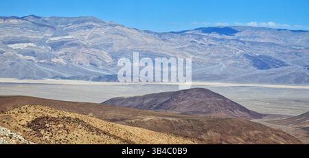 Farbenfrohe geschichtete Berge und trockene Ebenen im Death Valley, Kalifornien, mit dramatischer Geologie und Wüstenlandschaft unter klarem Himmel. Stockfoto
