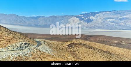 Farbenfrohe geschichtete Berge und trockene Ebenen im Death Valley, Kalifornien, mit dramatischer Geologie und Wüstenlandschaft unter klarem Himmel. Stockfoto