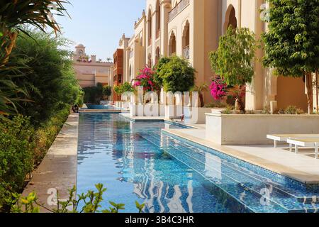 Luxuriöses Resort mit privatem Zugang zum Pool, tropischen Bäumen und mediterraner Architektur in einem sonnigen, exotischen Urlaubsziel. Stockfoto
