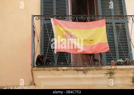 Die spanische Nationalflagge hängt auf dem Balkon eines Wohnhauses auf Mallorca, Spanien, und repräsentiert die nationale Identität und den städtischen Alltag. Stockfoto