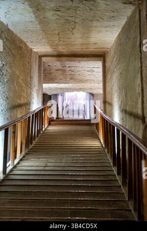 Eine schräge Aufnahme einer Treppe mit einem Holzgeländer, die nach oben in das helle Licht eines ägyptischen Grabes führt Stockfoto