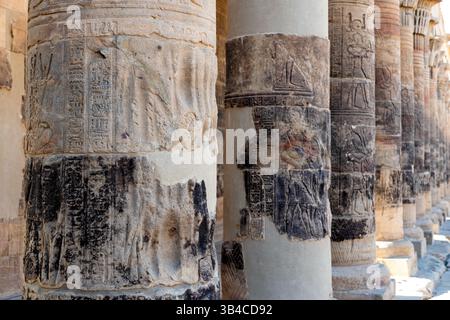 Verwitterte Säulen im Tempel von Edfu in Ägypten mit komplizierten Hieroglyphen und detaillierten Schnitzereien. Raue Textur und gedämpfte Farben Stockfoto