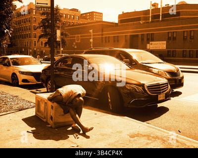 Obdachloser Mann, der auf dem Bürgersteig neben Luxusautos in Harlem unter intensiver Sommersonne schläft Stockfoto