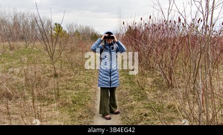 Während der Beobachtung nimmt eine weibliche Vogelbeobachterin an einer umweltbewussten Aktivität in einem Naturschutzgebiet Teil. Stockfoto