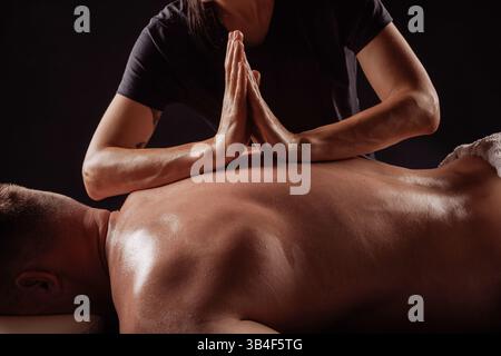 Nahaufnahme eines Therapeuten, der während der Tiefenmassagetherapie zur Muskelentlastung die Hände auf den Rücken des Mannes drückt. Stockfoto