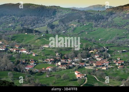 Idyllische Landschaft mit sanften grünen Hügeln und einem charmanten Dorf in einem Tal. Esles, santa maria de cayon, kantabrien, spanien Stockfoto