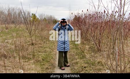 Während der Beobachtung nimmt eine weibliche Vogelbeobachterin an einer umweltbewussten Aktivität in einem Naturschutzgebiet Teil. Stockfoto