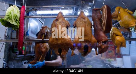Aufhängen von gebratenem Fleisch in einem traditionellen Restaurant, ganze Enten, Würstchen und andere Köstlichkeiten hinter einer Glasvitrine Stockfoto