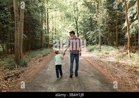 Vater und Sohn haben einen schönen Moment zusammen, als sie durch einen Wald spazieren. Stockfoto