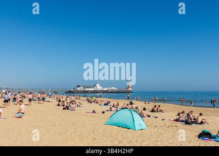 West Cliff Beach, Bournemouth, Großbritannien - 30. April 2025: Zelt und Sonnenanbeter vor dem Bournemouth Pier. Stockfoto