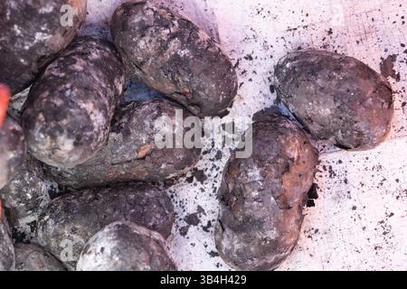 Kartoffeln aus Holzkohle, bedeckt mit Asche- und Emberresten Stockfoto