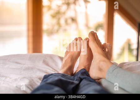 Nahaufnahme die Füße eines Paares entspannen sich im Bett zu Hause und genießen einen freien Wochenendtag. Liebes- und Beziehungskonzept Stockfoto