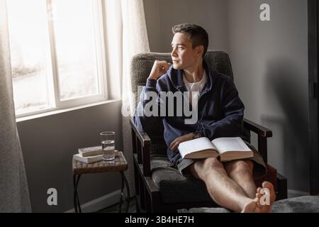 Nachdenklicher junger Mann, der einen Tag zu Hause entspannt liest. Stockfoto