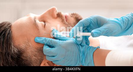 Kosmetologe macht Beauty-Injektionen für Mann mittleren Alters Stockfoto