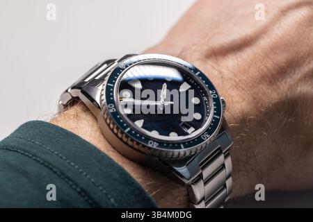 Eine detaillierte Nahaufnahme einer modernen Armbanduhr mit Edelstahlarmband, die von einer Person getragen wird, zeigt ihr elegantes Design und ihre subtilen Details in natürlicher Natur Stockfoto