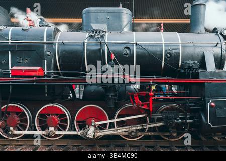 Nahaufnahme einer leistungsstarken Vintage-Dampflokomotive. Zeigt die großen roten Räder und komplexe Maschinenbau Stockfoto