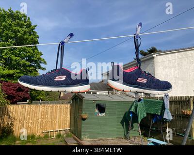 Zwei Skechers hängen an einer Wäscheleine im Garten, um sie nach dem Entnehmen aus der Waschmaschine zu trocknen Stockfoto