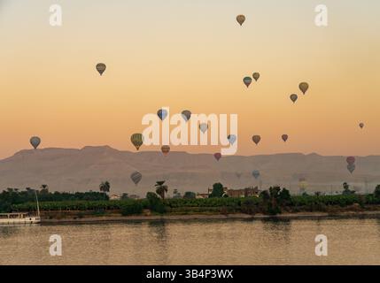 Viele Ballons am Himmel über dem Nil in Luxor für einen Flug bei Sonnenuntergang über dem Tal der Könige Stockfoto