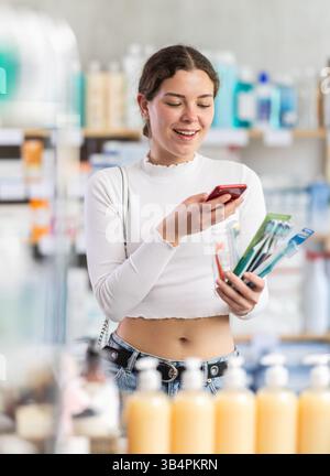 Junge Frau scannt Barcode von Zahnnetzverpackungen in der Apotheke Stockfoto