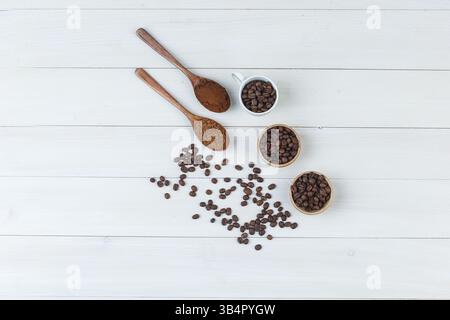 Einige Kaffeebohnen mit gemahlenem Kaffee in der Tasse und Schüsseln auf hölzernem Hintergrund, Blick von oben. Stockfoto