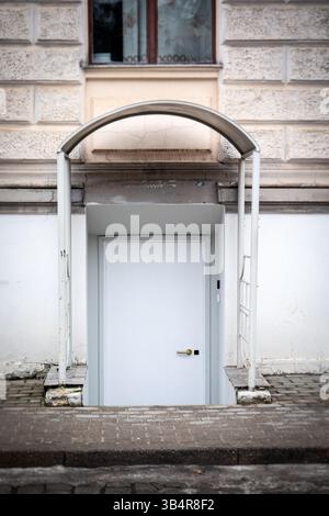 Weiße Tür mit Bogengang zum Keller in urbaner Umgebung. Stockfoto