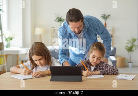 Vater hilft zwei Kindern bei Hausaufgaben, unterstützt sie beim Lernen und Lernen zu Hause. Stockfoto