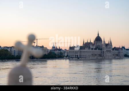 Budapest, Ungarn – 22. September 2024: Nationalkreuzsymbol gegen Parlament – das geneigte Kruzifix steht feierlich vor Budapests großem Wahrzeichen Stockfoto