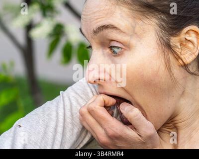 Eine Nahaufnahme einer Hirschzecke, die am Arm einer Person herumkriecht. Die Arachnide ist rötlich gefärbt und hat ihre Beine als Kriechen ausgestreckt Stockfoto
