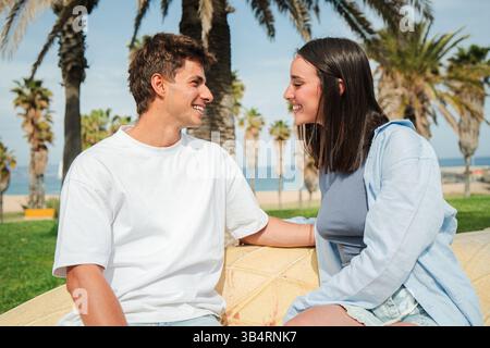 Ein fröhliches Paar führte ein herzliches Gespräch, während es zusammen in einer schönen Umgebung saß, Lächeln und Lachen teilte und einen Moment schuf Stockfoto