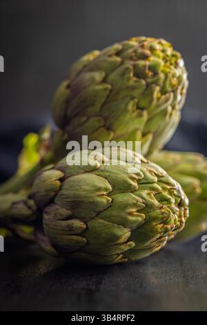 Reife Artischocken Pflanzen auf einem schwarzen Tisch. Stockfoto