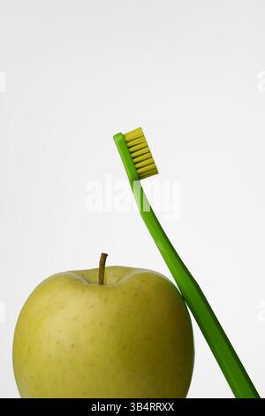 Mundhygiene mit grünem Apfel und grüner Zahnbürste auf hellgrauem Hintergrund. Mundgesundheit. Stockfoto